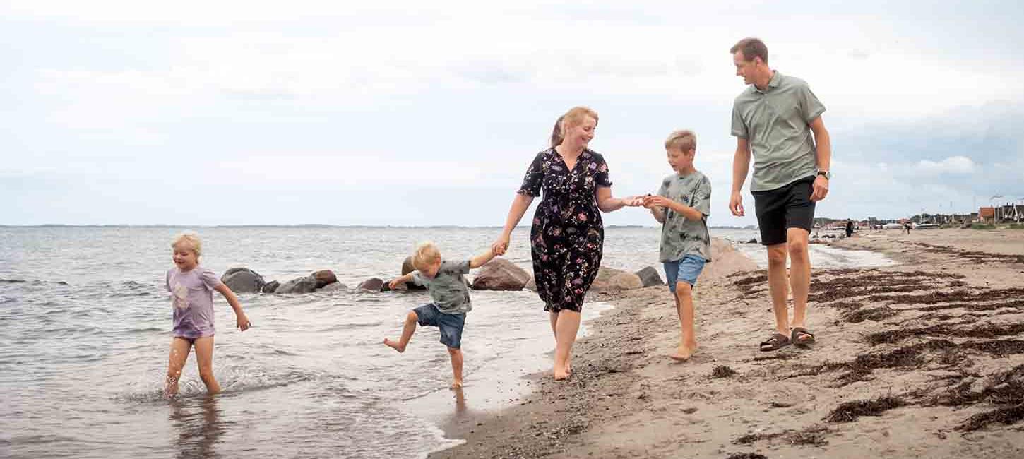 Familie går tur på stranden ved Hasmark