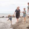 Familie går tur på Hasmark Strand og leger i vandet