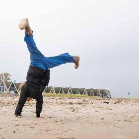 Barn slår vejrmøller på Hasmark Strand i efteråret med sommerhuse i baggrunden